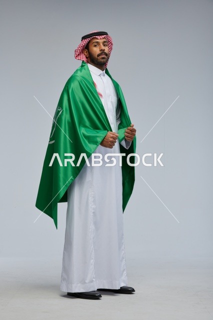 رجل سعودي يرتدي علم المملكة في استوديو تصوير