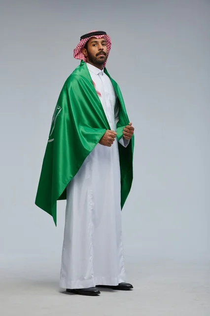 رجل سعودي يرتدي علم المملكة في استوديو تصوير