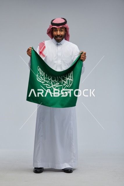 رجل سعودي يحمل علم المملكة العربية السعودية