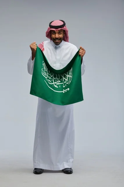 رجل سعودي يحمل علم المملكة العربية السعودية في استوديو
