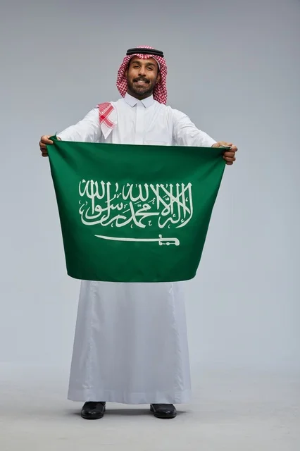 رجل سعودي يحمل علم المملكة العربية السعودية في استوديو