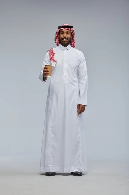رجل سعودي بالزي التقليدي يمسك كوب قهوة