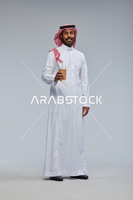 رجل سعودي بالثوب التقليدي يحمل كوب قهوة