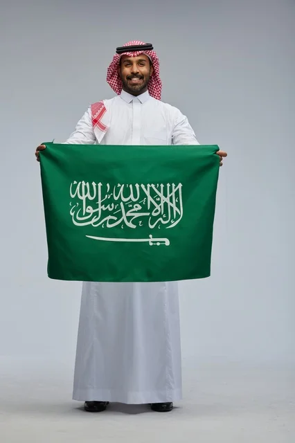 رجل سعودي يحمل علم المملكة بالزي التقليدي