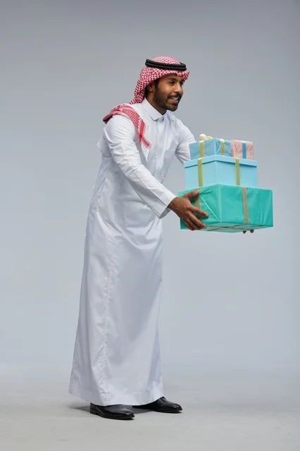 رجل سعودي يحمل مجموعة صناديق هدايا في الاستوديو