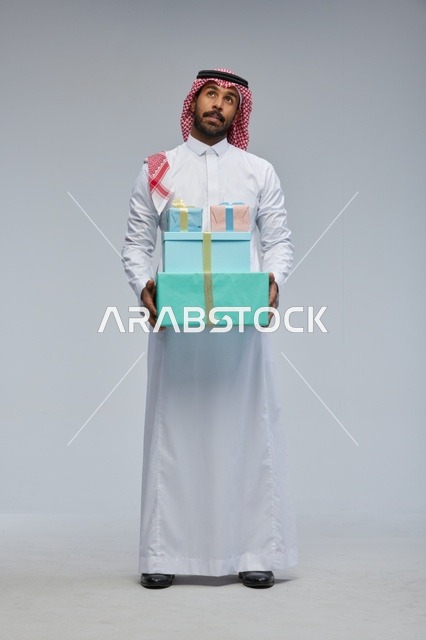 Saudi Man Holding Gift Boxes on Grey Background