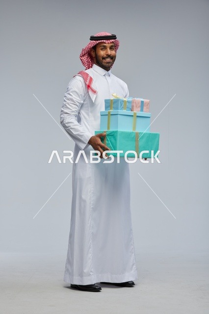 رجل سعودي يحمل علب هدايا بالزي التقليدي