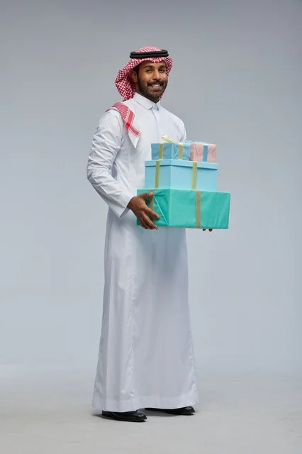 رجل سعودي يحمل علب هدايا بالزي التقليدي