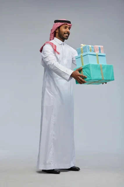 Saudi Man Holding Gift Boxes in Traditional Dress Saudi Man Holding Gift Boxes in Traditional Dress