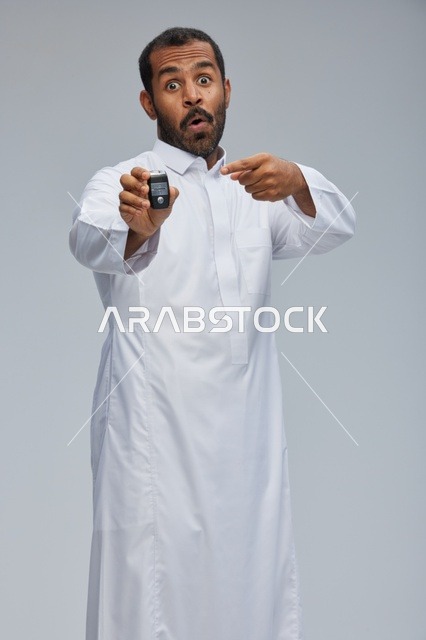 رجل سعودي يحمل مفتاح سيارة بتعبير مندهش