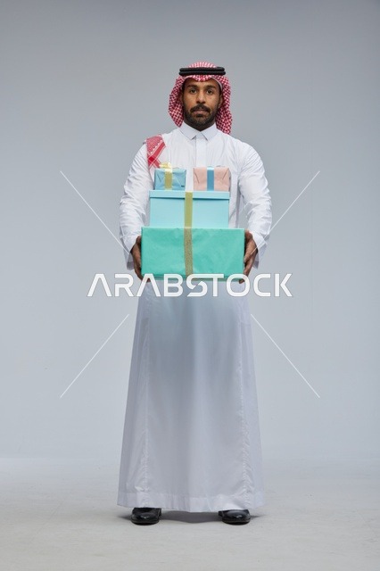 رجل سعودي يحمل علب هدايا ملونة في تصوير استوديو