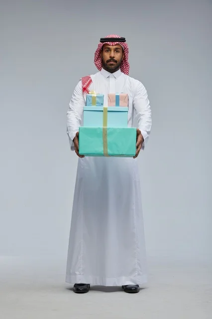 رجل سعودي يحمل علب هدايا ملونة في تصوير استوديو
