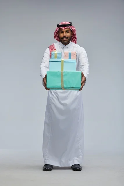 رجل سعودي يحمل علب هدايا بالزي التقليدي