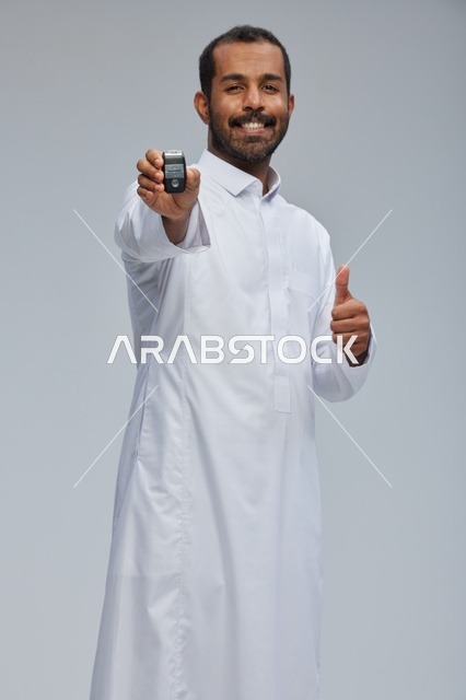 رجل سعودي يحمل مفتاح سيارة مع إيماءة النجاح