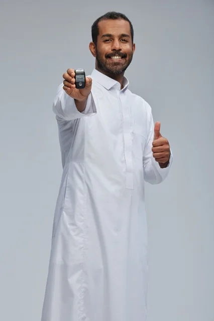 رجل سعودي يحمل مفتاح سيارة مع إيماءة النجاح
