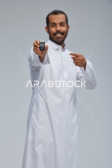 رجل سعودي يحمل مفتاح سيارة في الاستوديو