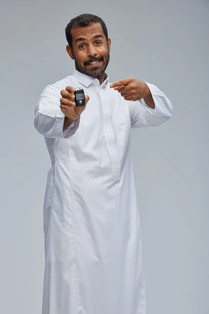 رجل سعودي بالثوب التقليدي يمسك مفتاح سيارة