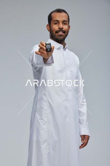 رجل سعودي يحمل مفتاح سيارة في الاستوديو