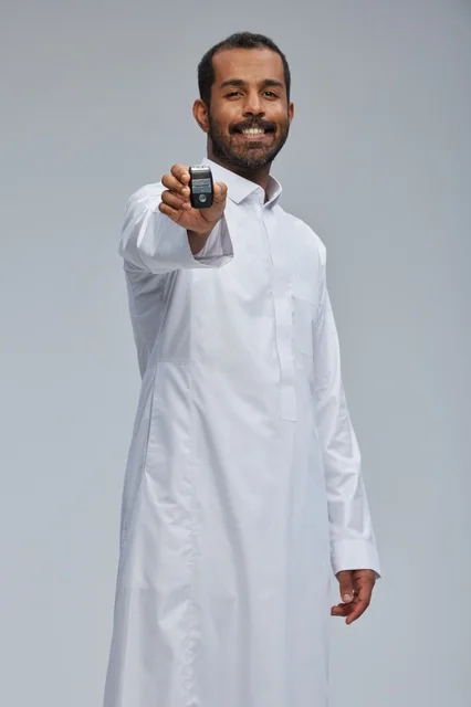 رجل سعودي بالثوب يحمل مفتاح سيارة في الاستوديو