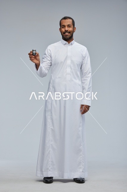 رجل سعودي بالثوب الأبيض يحمل مفتاح سيارة