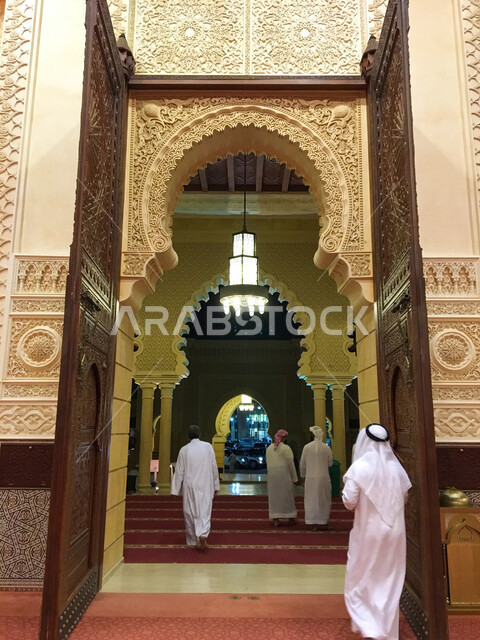 A picture from the back of a group of worshipers inside the Bin Hamouda Mosque in Al Ain in the Emirate of Abu Dhabi, the atmosphere of the blessed Ramadan, Islamic decoration, United Arab Emirates, worship and getting closer to God