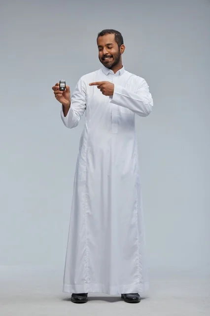 رجل سعودي يحمل مفتاح سيارة أمام خلفية رمادية