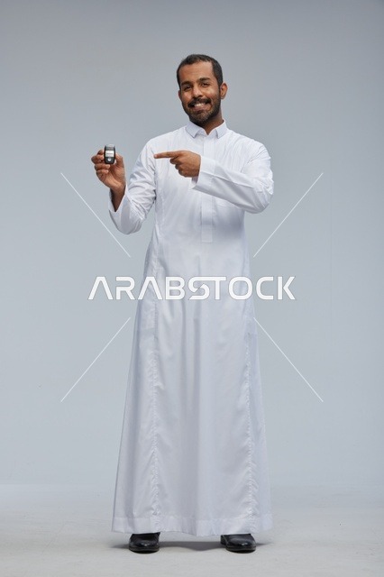 رجل سعودي يحمل مفتاح سيارة في استوديو
