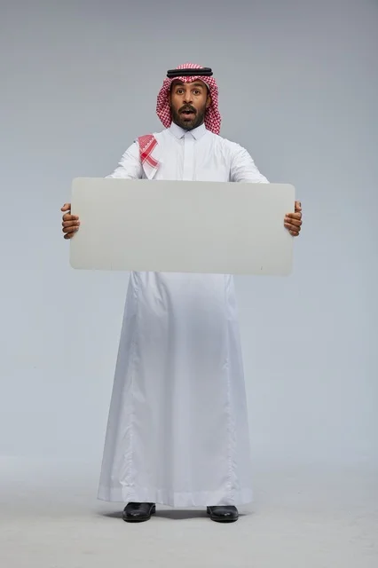 رجل سعودي مندهش يحمل لوحة بيضاء فارغة