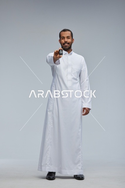 رجل سعودي بالثوب الأبيض يحمل مفتاح سيارة