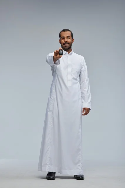 رجل سعودي بالثوب الأبيض يحمل مفتاح سيارة