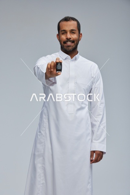 رجل سعودي يحمل مفتاح سيارة في الاستوديو