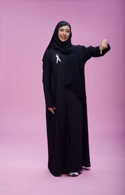 امرأة سعودية مع شريط التوعية بسرطان الثدي خلفية وردية