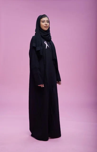 امرأة سعودية مع شريط سرطان الثدي بخلفية وردية