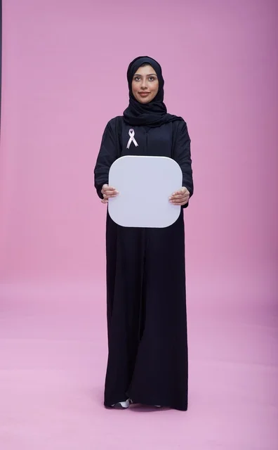 امرأة سعودية تحمل لوحة فارغة للتوعية على خلفية وردية