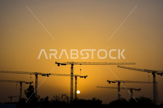 صورة لرافعات البناء وقت الغروب في مدينة العين بإمارة أبو ظبي ، الإمارات العربية المتحدة ، جمال الغروب في سماء الإمارات