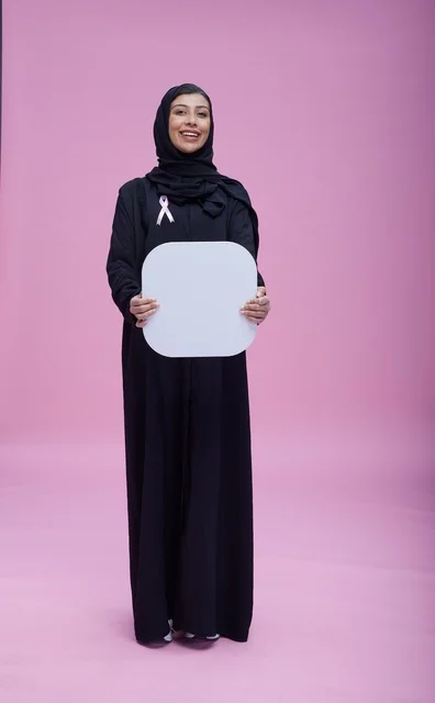 امرأة سعودية تحمل لوحة بيضاء فارغة بخلفية وردية