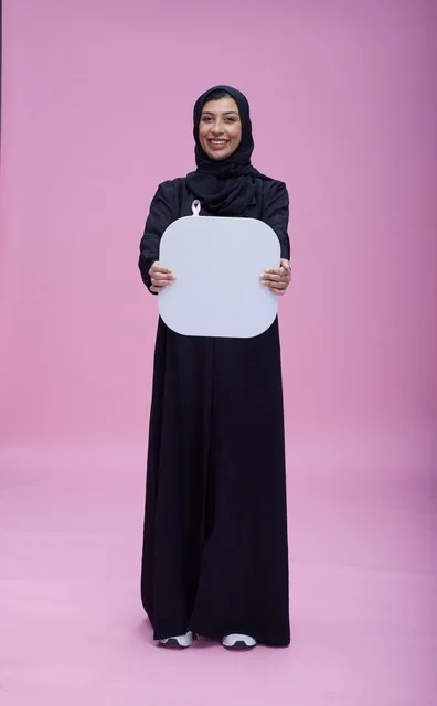 امرأة سعودية تحمل لوحة فارغة على خلفية وردية