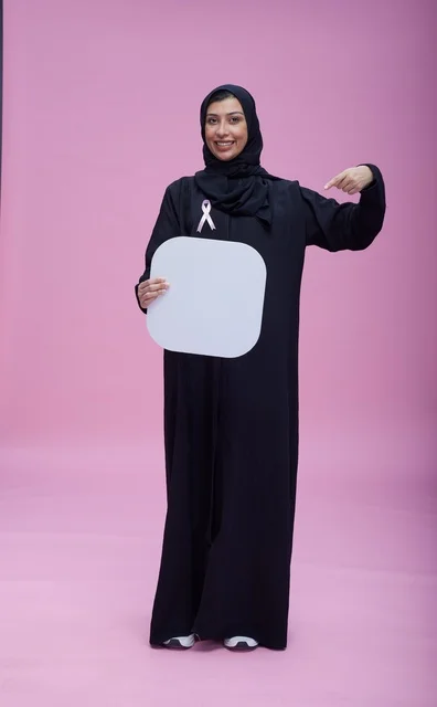 امرأة سعودية تحمل لوحة فارغة وشعار سرطان الثدي