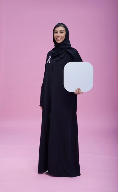 امرأة سعودية تحمل لوحة بيضاء فارغة بخلفية وردية
