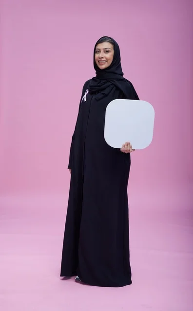 امرأة سعودية تحمل لوحة بيضاء فارغة بخلفية وردية