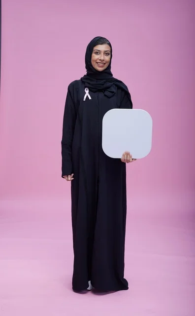 امرأة سعودية تحمل لوحة بيضاء فارغة بخلفية وردية