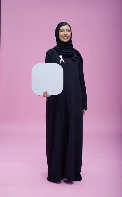 امرأة سعودية تحمل لوحة فارغة أمام خلفية وردية استوديو