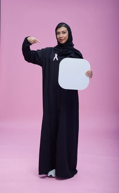 امرأة سعودية تحمل لوحة فارغة على خلفية وردية