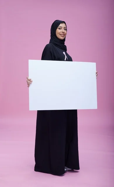 امرأة سعودية تحمل لافتة فارغة للتوعية بسرطان الثدي