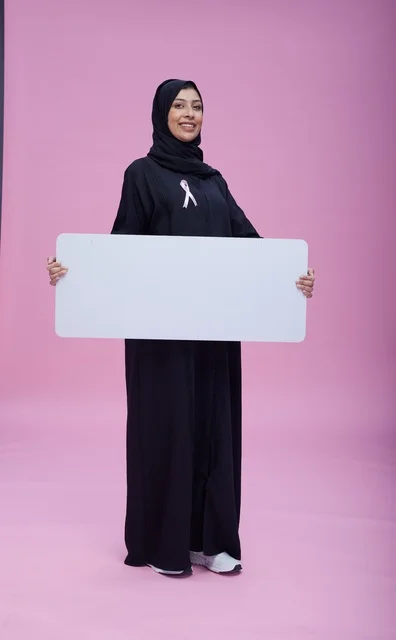 امرأة سعودية تحمل لوحة فارغة للتوعية بسرطان الثدي
