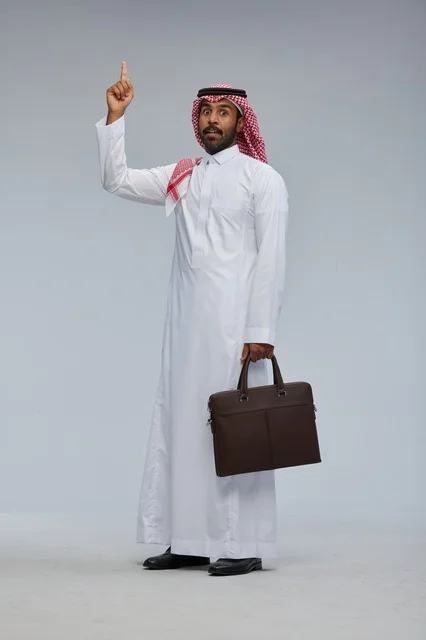 رجل أعمال سعودي يشير للأعلى مع حقيبة جلدية