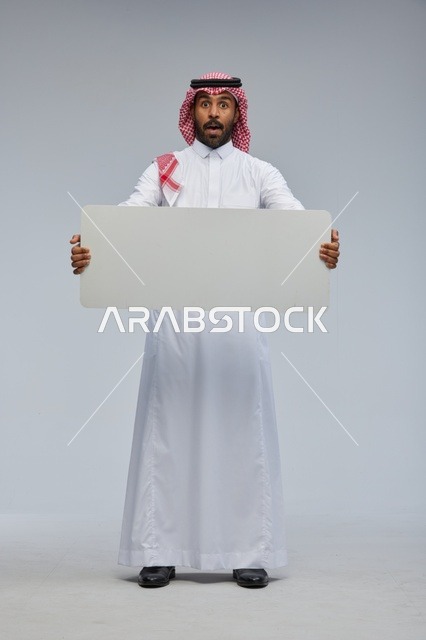 رجل سعودي مندهش يحمل لوحة بيضاء فارغة