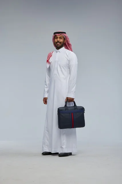 رجل أعمال سعودي يحمل حقيبة عمل بالزي التقليدي