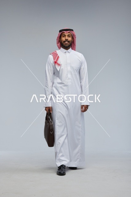 رجل أعمال سعودي يمشي حاملاً حقيبة في الاستوديو