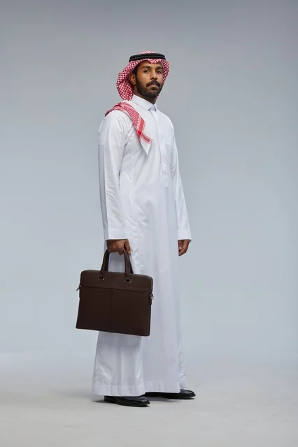 رجل أعمال سعودي بحقيبة عمل على خلفية رمادية
